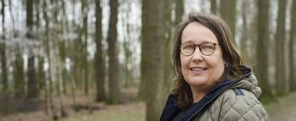 twee vrouwen in bos, een kijkt in camera, ander op een boomstam ver weg, kijkt weg