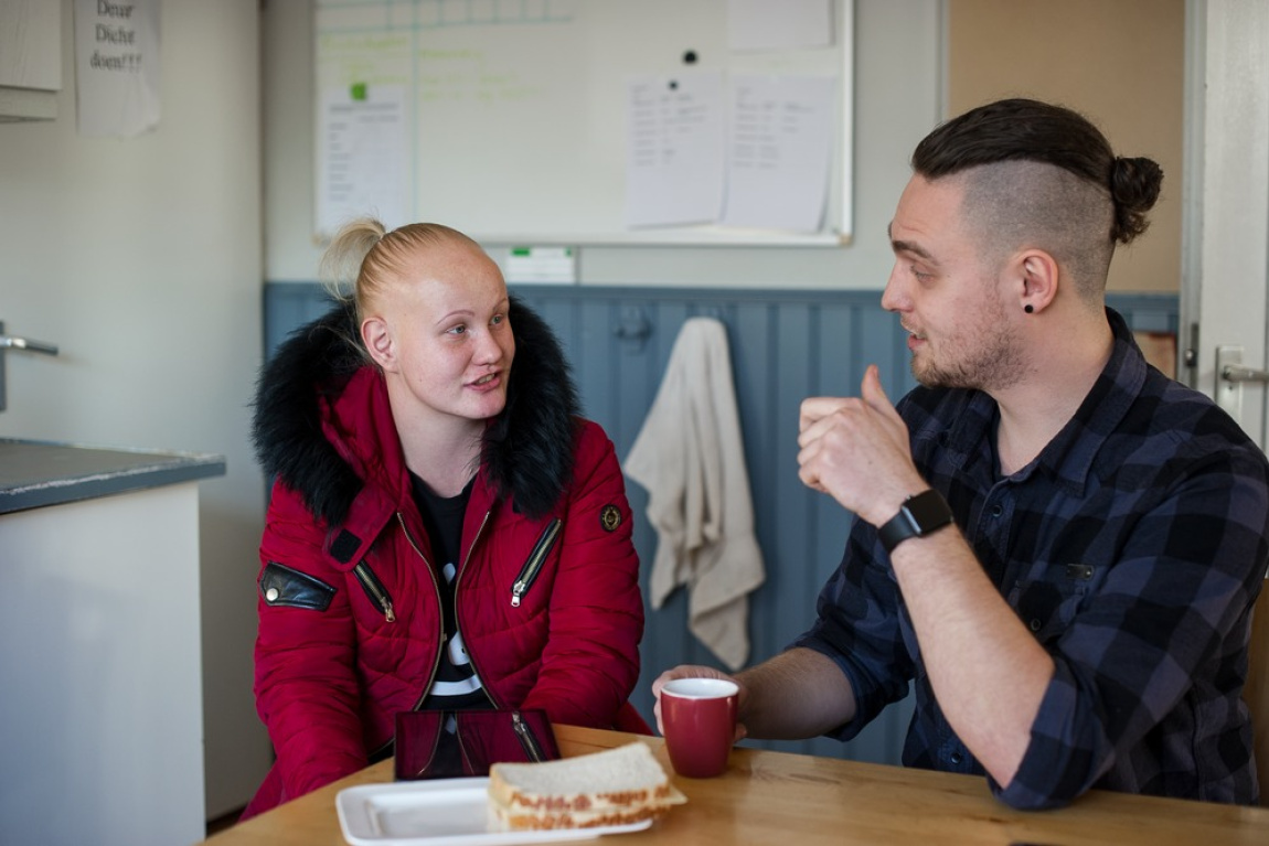 Vrouw en man praten zittend aan de keukentafel met lunch