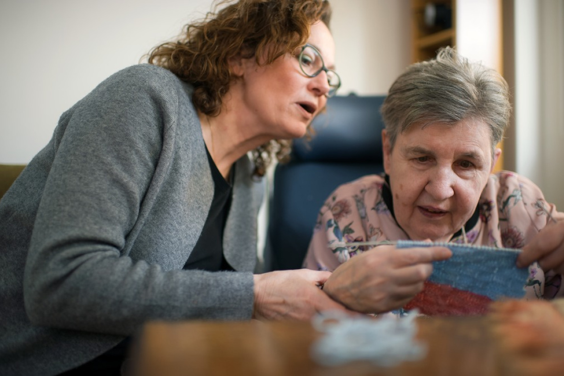 Vrouw kijkt mee met breiwerk andere vrouw