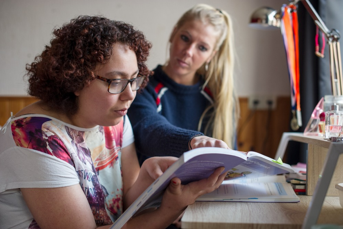 Vrouw helpt jonge vrouw met huiswerk