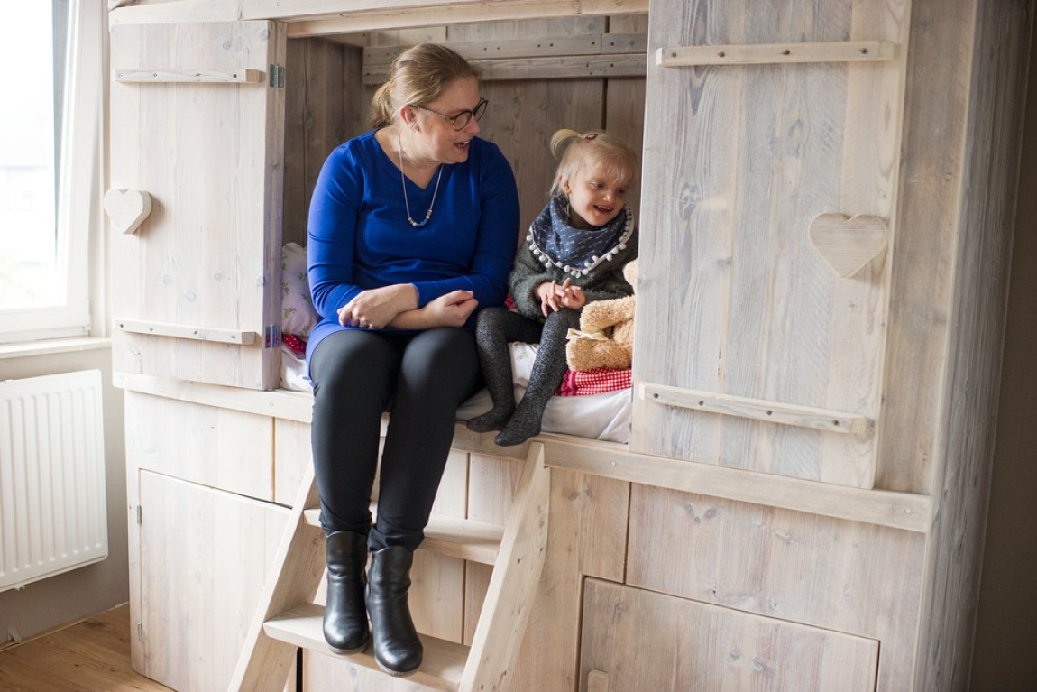 Vrouw en kind op de rand van een bedstee