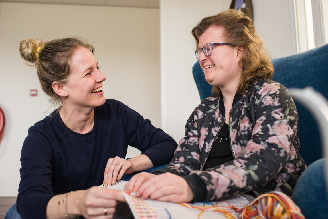 Vrouwen lachen bij borduurwerk
