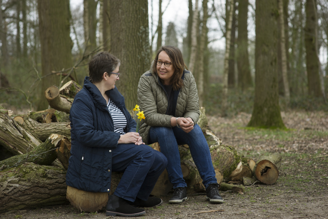 Twee vrouwen op een boomstronk, in gesprek