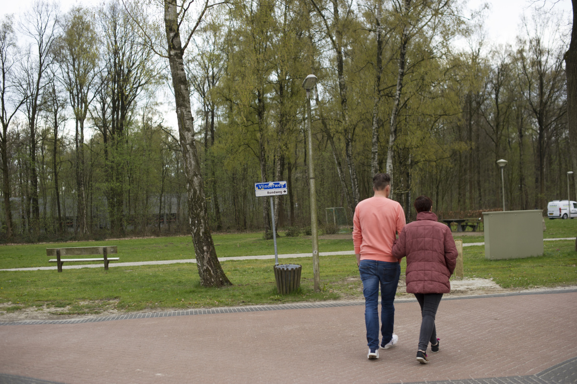 Man en vrouw lopen gearmd over een weg in het groen
