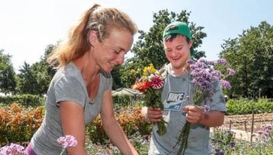 Dame en jongen werken lachend in de tuin met bloemen