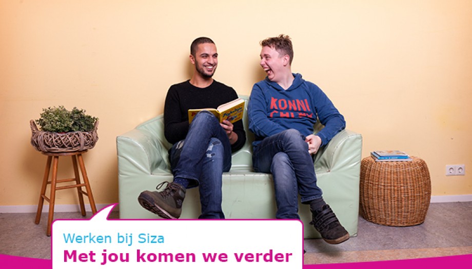 Twee mannen lezen lachend een boek op ene bank