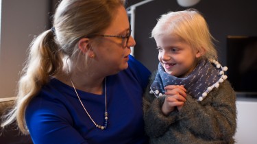 Begeleidster heeft client, jong meisje, op schoot
