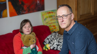 Man op voorgrond, meisje met teddybeer op achtergrond