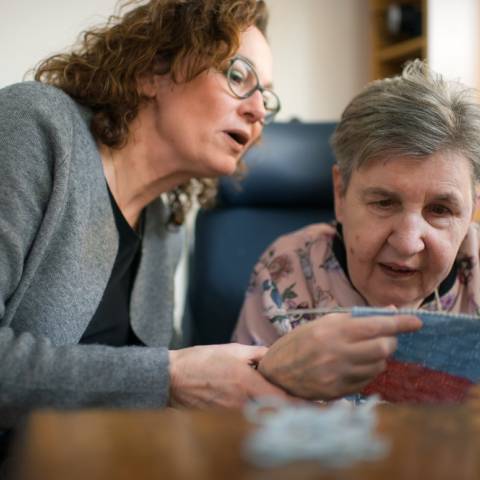 Vrouw kijkt mee met breiwerk andere vrouw