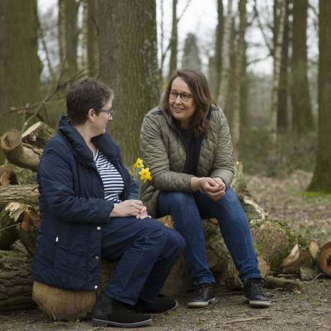 Twee vrouwen op een boomstronk, in gesprek