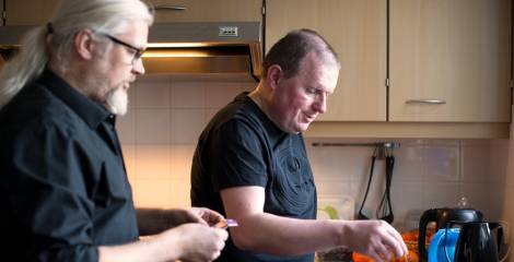 Twee mannen staan in de keuken en zetten thee