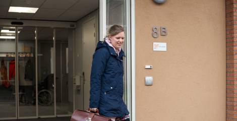 Vrouw loopt naar buiten met dokterstas in de hand