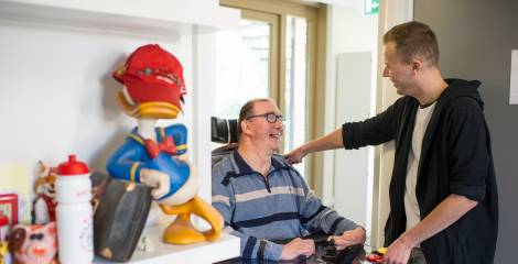 Begeleider verwelkomt man in rolstoel in de kamer