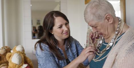 Vrouw die een vrouw helpt met haar sieraden